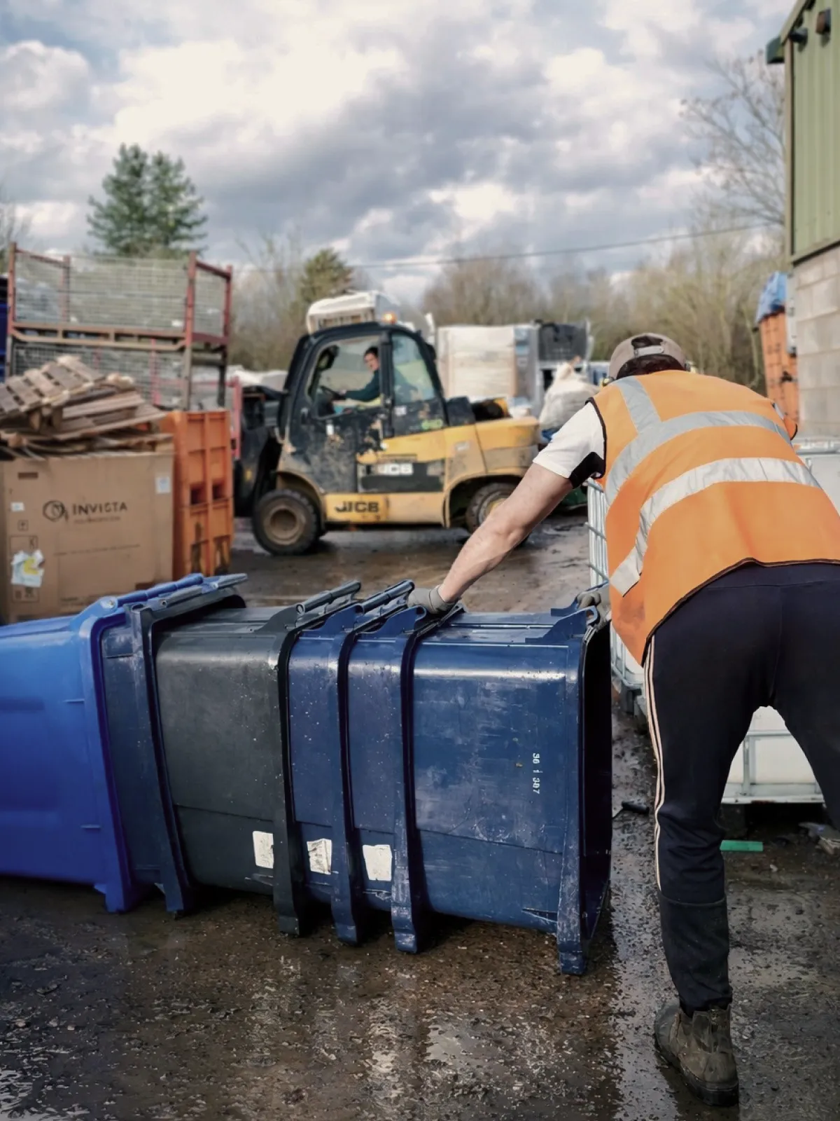 Worker handling recycling containers at Repro Plastics
