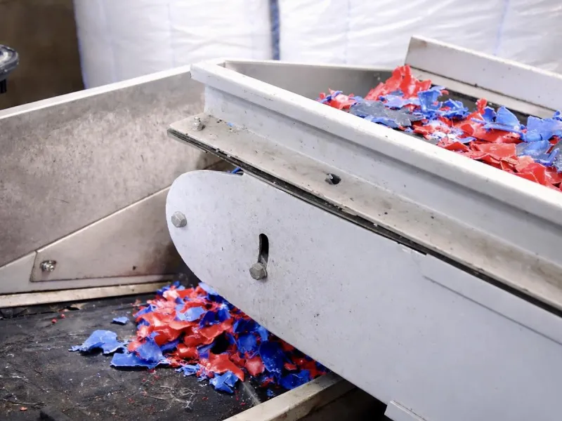 Shredded red and blue plastic on a metal processing machine